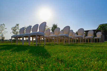 Rows of white empty chairs on a lawn before a wedding or ceremonyの写真素材