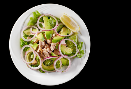 Tuna salad with avocado and arugula on a white plate, on a black background.の写真素材