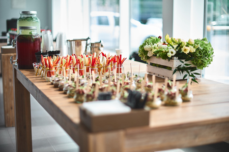 Tasty appetizers with wooden spoons served in glass jars on wooden table.