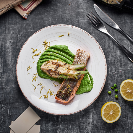 Baked salmon steak with mashed green peas , caramelized onions and lemon.
