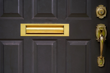 Close up outdoor view of part of door, dark brown. yellow handle and and mailbox. Mailbox slot incorporated. Abstract object image.の写真素材