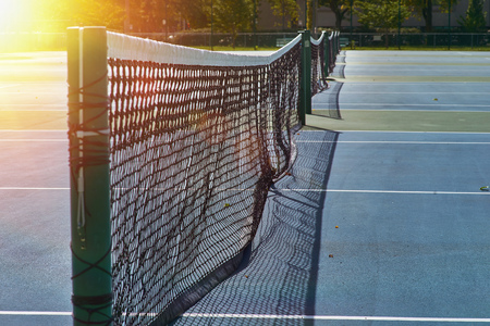 Tennis net with bokeh nature in the background.soft focus. Sunshine over a tennis court in a public park.の写真素材
