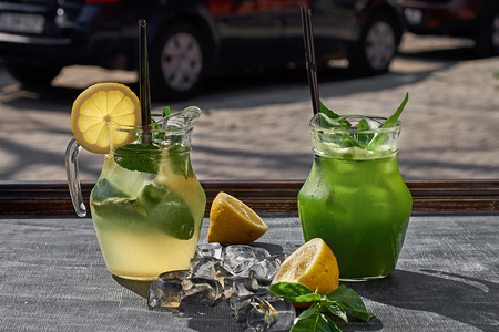 Lemonade with cucumbers, lemons and mint leafs in glasses on wooden tableの写真素材