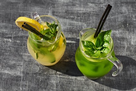 Lemonade with cucumbers, lemons and mint leafs in glasses on wooden tableの写真素材
