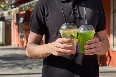 Two lemonade in the hands of the man. fresh cucumber and lemon drinks. Close up.の写真素材