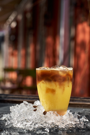 Orange and coffee cocktail, glass among ice on a wooden background, with space for your text....
