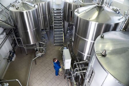 Chisinau, Moldova, March 13, 2019: A worker in a blue uniform at the control panel of a brewery, monitors performance in a modern brewery in Moldova.のeditorial素材