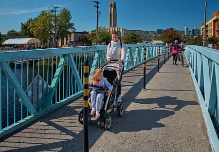Montreal, Canada - June 2 2016: girl with a stroller and a little girl are crossing the bridge over the Lachine Canal. travel in Canadaのeditorial素材
