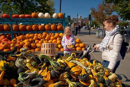 Montreal, Quebec, Canada, September 14, 2018: During the fall season, mom and daughter pick a pumpkin,on the sidewalk near Place du Marche , Avenue Atwater, Montreal Travels in Canadaのeditorial素材