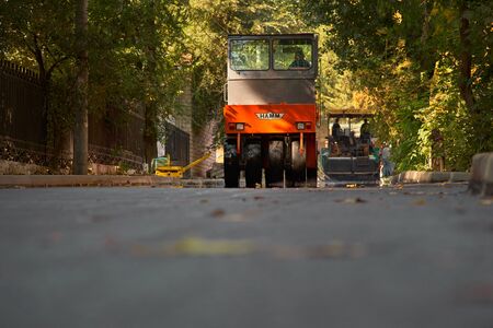 Chisinau, Moldova, March 25, 2019: Industrial landscape with rollers that rolls a new asphalt in the roadway. Repair, complicated transport movement. New, freshly-laid asphalt on the road. Construction of roads.のeditorial素材