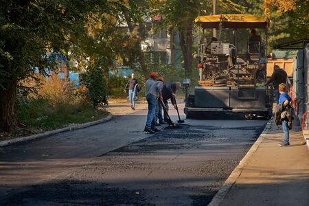 Chisinau, Moldova, March 25, 2019: Team pave the roadway. Worker operating the process of building new asphalt road on the new road constructionのeditorial素材
