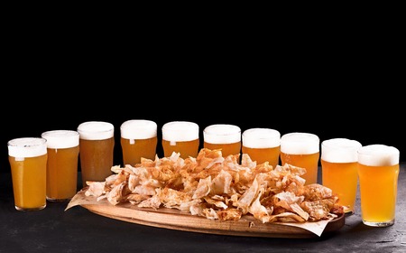 Beer set for a large group of friends. Beer in glasses closeup on the concrete table. Beer and snacks are crispy chips on a wooden tray. Copy space. Drink and snack for the football match or party.の写真素材
