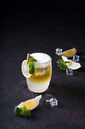 Moscow Mule Cocktail on a dark background. Cold drink, Layered white and yellow with vodka, spicy ginger beer, and lime juice. Selective focus.Cocktail card. Copy space.の写真素材