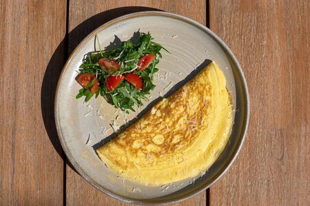 Breakfast. Omelet with tomatoes, arugula, cheese on a blue plate. Frittata - Italian omelette. Top...
