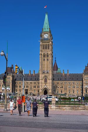 Ottawa, Ontario, Canada September 18, 2018: Vertical frame where the police and tourists at the pedestrian crossing against the background of the Central Block and Peace Tower in Parliament Hill.のeditorial素材
