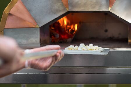 The baker shows a freshly baked focaccia, on the peel. baking Italian focaccia with olive oil and...
