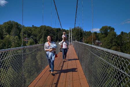 Coatikuk, Quebec, Canada September 8, 2018: Joyful tourists on the longest suspension pedestrian...