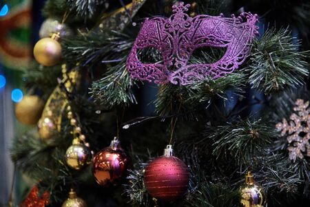 Beautiful carnival mask hanging on the Christmas tree in the background of bright Christmass decorations.の写真素材