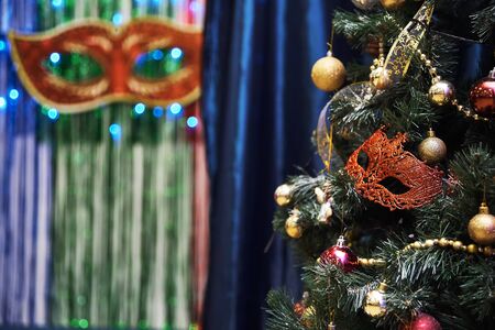 Beautiful carnival mask hanging on the Christmas tree in the background of bright Christmass decorations.の写真素材