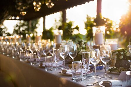 Outdoor wedding celebration at a restaurant. Festive table setting, catering. Wedding in rustic style in summer, beautiful small bouquets on a table. selected focusの写真素材