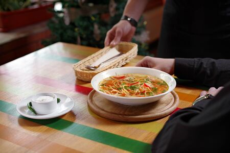 Man was served a bowl of soup with chicken, vegetables and noodles, a with sour cream and a spoon, place for text. Traditional Russian or Moldavian, Romanian or Ukrainian food is called Zama.の写真素材