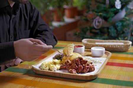 Man eats in a restaurant, close up.Traditional russian or moldavian or romanian or ukrainian food called mamaliga. Italian traditional Polenta, porridge made from cornmeal. Mamaliga With Cottage Cheese,meat and sour cream.の写真素材