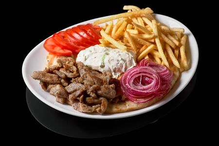 Close up of traditional Greek dish called Gyros pita and fries or Greek pie with roast beef salad. Grilled meat with fried potatoes and vegetable salad Isolated on black Backgroundの写真素材