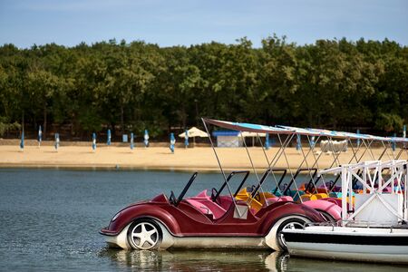 Catamarans in the form of cars at the pier on the lake
