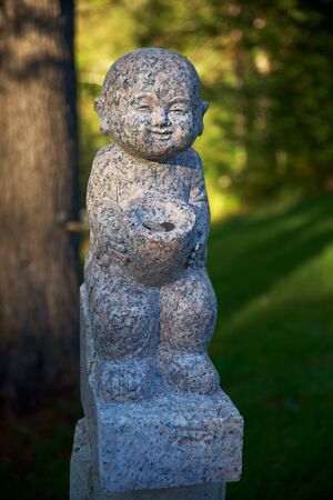 Harrington, QC, Canada - September 23, 2018: Small funny marble figurines in the territory of a Buddhist temple. Every the statue is responsible for various matters, visitors put coins to them.のeditorial素材