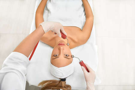 woman close up receiving electric facial massage on microdermabrasion equipment at beauty salon. rf...
