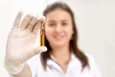 Cosmetic ampoule, a woman in the beauty salon. Vitamin in cosmetic ampoule. Hyaluronic acid....