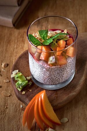 dessert yogurt with chia seeds and fruits persimmon on a wooden dark background. Healthy vegan, vegetarian breakfast table, ingredients on tableの写真素材