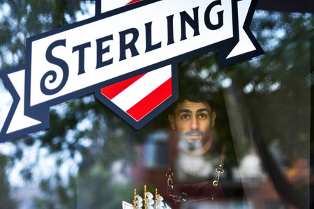 Young hairdresser at his hairdresser. a man with a beard is standing by the window and looking at...