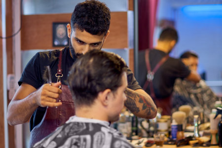 Master cuts hair and beard of men in the barbershop, hairdresser makes hairstyle for a young man.