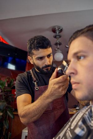 Master cuts hair and beard of men in the barbershop, hairdresser makes hairstyle for a young man. Work in the Barber shop, The process of the hairdresser.の写真素材