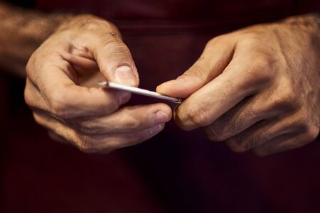 Cropped image of barber in stylish classic wear holding a straight razor.