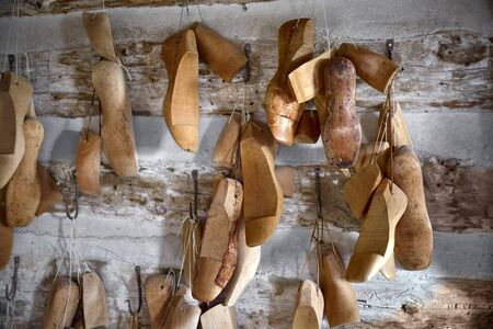 Various vintage wooden shoe lasts in a row on the old walls of the workshop.