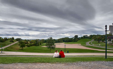 Couple of man and woman sitting on the lawn in Battlefield National Park in Quebec City. Traveling in Canada.のeditorial素材