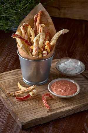 Takeaway food. french fries and vegetables in batter, carrots, sweet peppers, cured and sauces on a...