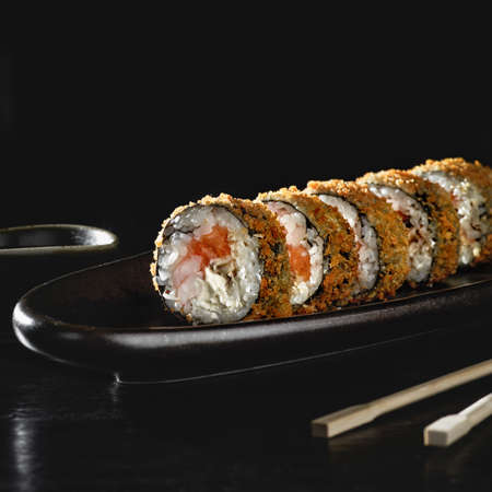 Hot fried sushi roll with salmon. Sushi menu. Japanese food. Hot fried sushi roll on black backgroundの写真素材