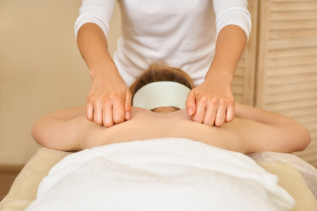 Professional massage the woman makes a back massage to a young girl in the spa salon, closeup the work of the masseur. Professional massage concept. Body care concept.の写真素材