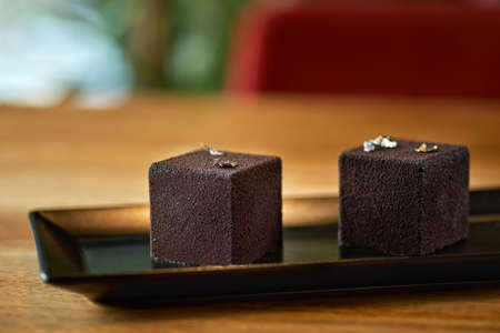 Modern mousse cake covered with chocolate velor. Dessert French cuisine on the table, serving in a...