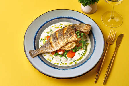 Close up of oven baked fish on on a yellow background. Healthy seafood.の写真素材