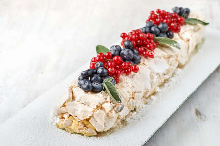 Meringue dessert Pavlova cake with fresh berries on top on a light wooden background. Copy spaceの写真素材