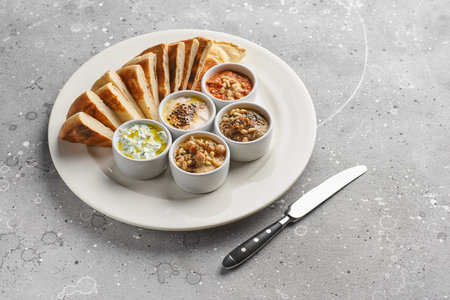 Mediterranean snack set on a stone texture. Hummus, olives, peppers, yogurt, beans. Greek food....