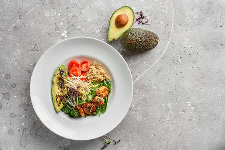Close-up, Bowl with tiger prawns, quinoa and avocado and olive oil on gray stone background.