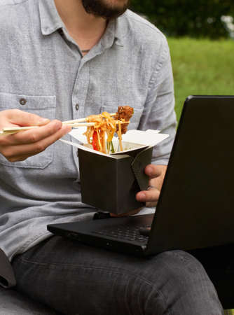 man enjoying food which he ordered food. Lunchtime at the park outdoors. Asian cuisine. food delivery concept, fast foodの写真素材