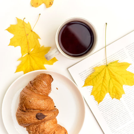 croissant with coffee on the background of a heap of books. Student eating breakfastの写真素材