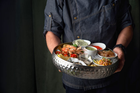Metal tray with open oysters, raw mussels in the chef's hands. Assorted seafood. Free space for text.の写真素材