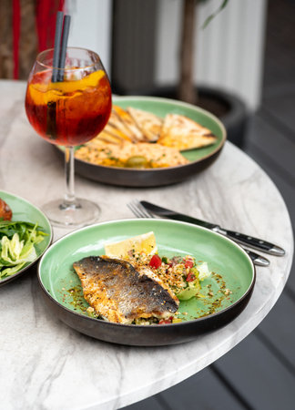 Food on the table summer terrace, grilled sea bass fillet and hummus. Vertical image with selective focus.の写真素材